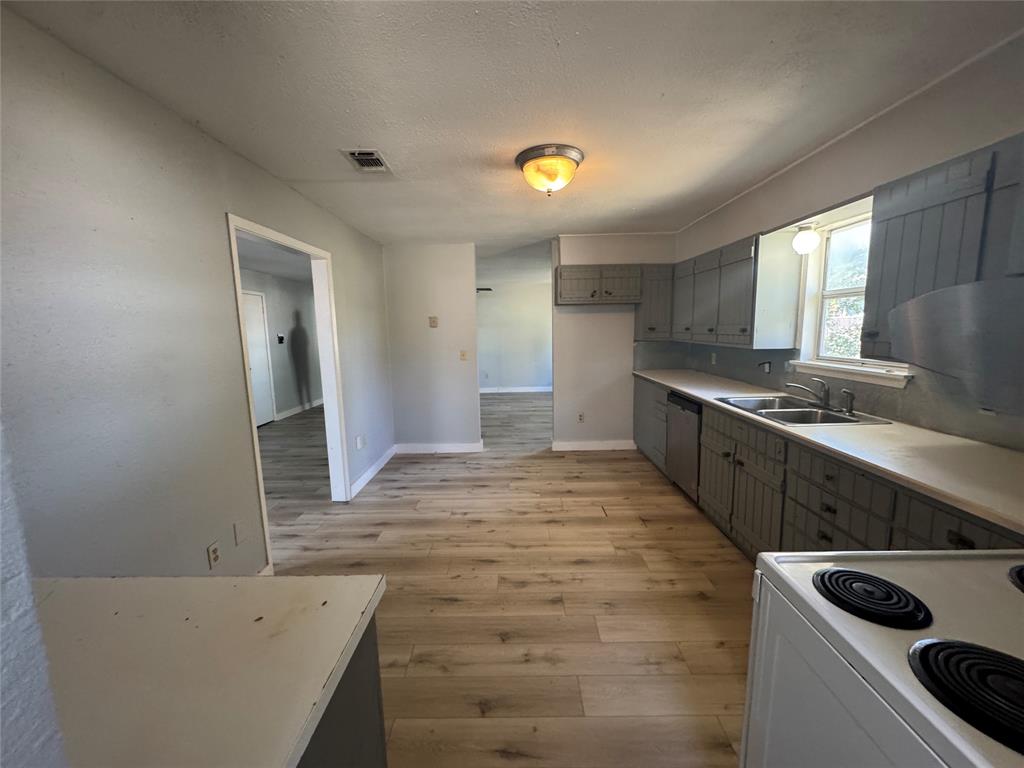 402 North Hughes Street Howe, TX 75459 - Photo 17 of 17 Kitchen with gray cabinetry, white range with electric stovetop, light wood finished floors, light countertops, and a textured ceiling