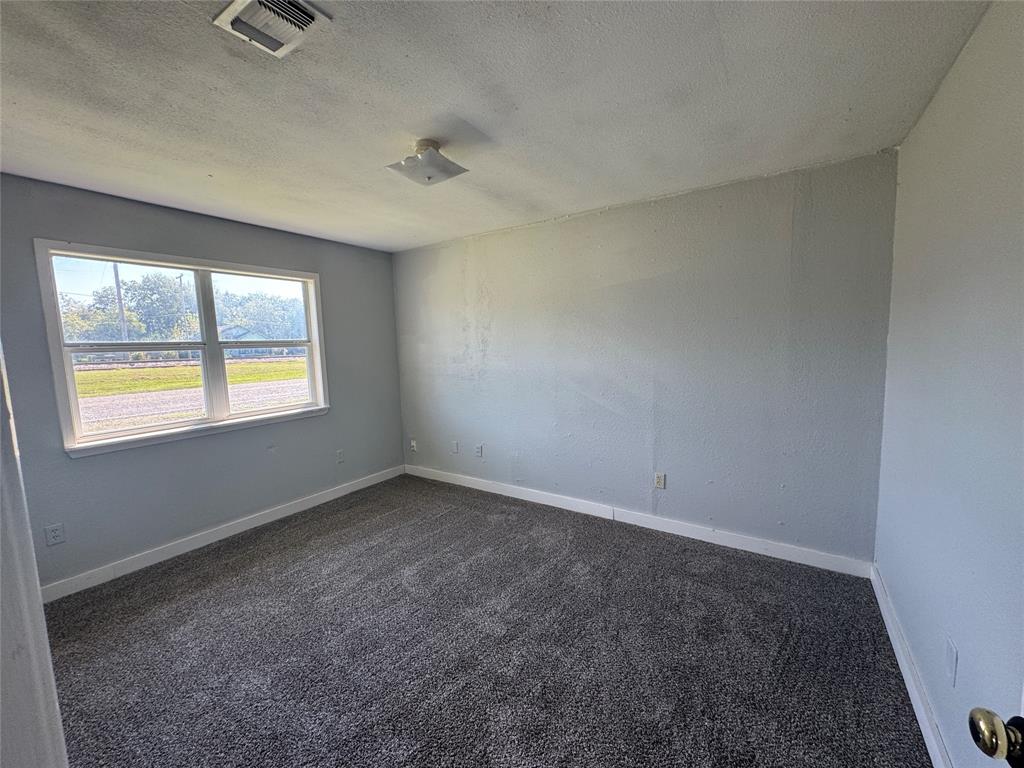 402 North Hughes Street Howe, TX 75459 - Photo 9 of 17 Spare room featuring dark carpet and a textured ceiling