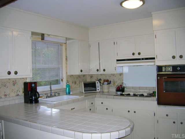 417 Harvard Street Raleigh, NC 27609 - Photo 3 of 9 a kitchen with granite countertop a stove a sink a refrigerator and white cabinets