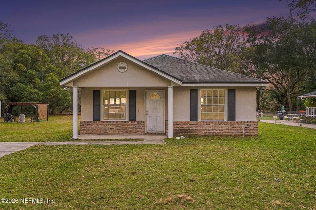 a view of a house with a yard and large tree