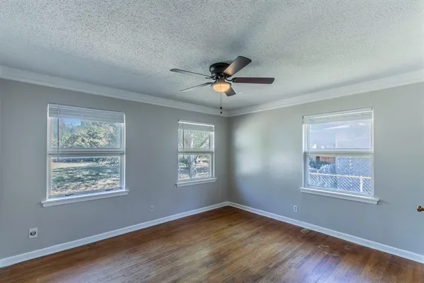 a view of an empty room with a window and wooden floor