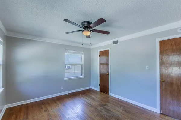 an empty room with wooden floor closet and fan