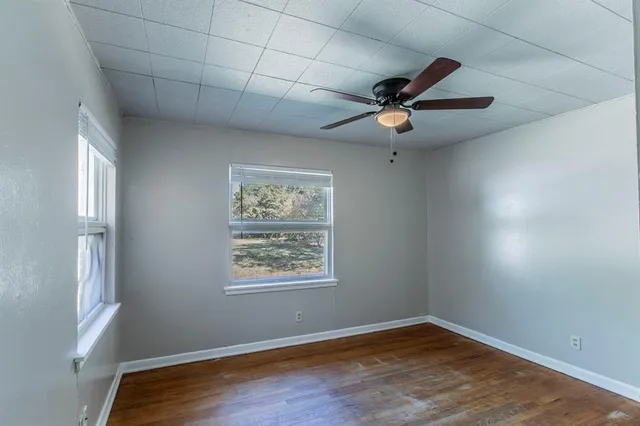 a view of an empty room with a window and wooden floor