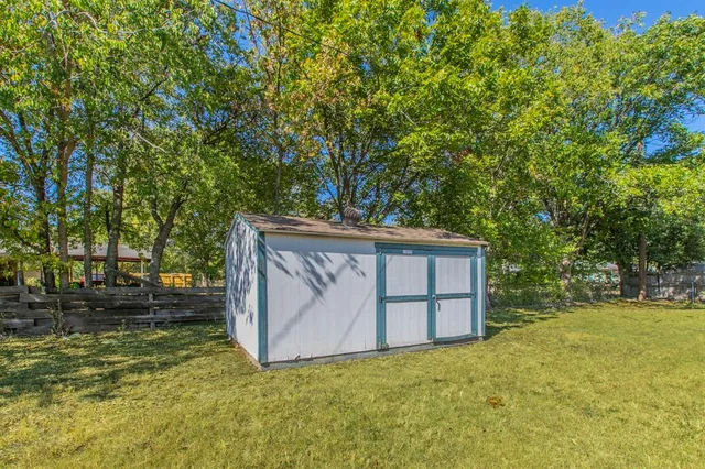 a backyard of a house with large trees and plants