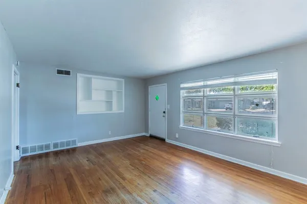 an empty room with wooden floor and windows