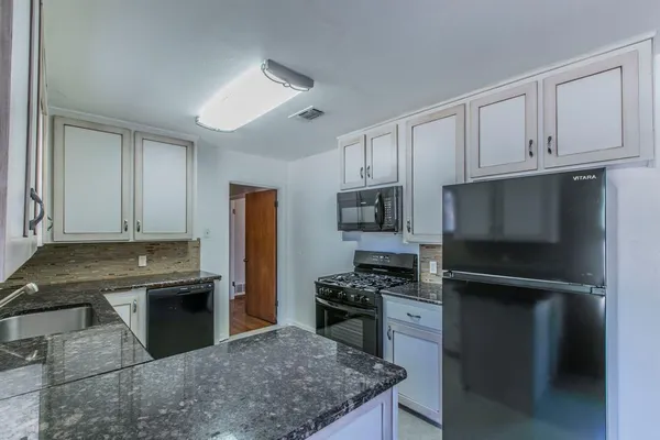 a kitchen with granite countertop a refrigerator stove and sink