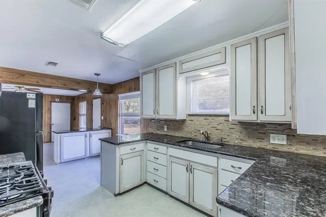 a kitchen with granite countertop a stove sink and cabinets