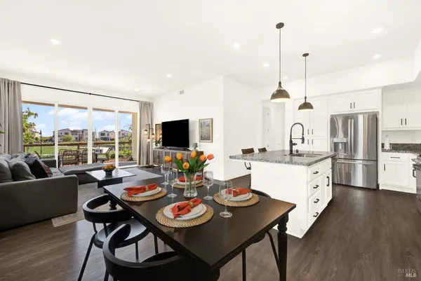 a open dining room with stainless steel appliances furniture a large window and a kitchen view