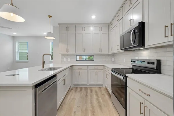 a kitchen with stainless steel appliances granite countertop a sink a stove a microwave and wooden cabinets