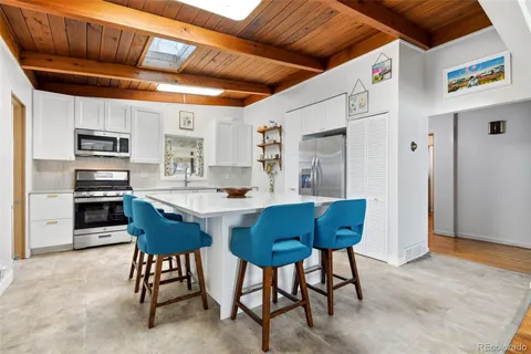 a kitchen with stainless steel appliances kitchen island granite countertop a table chairs and a refrigerator