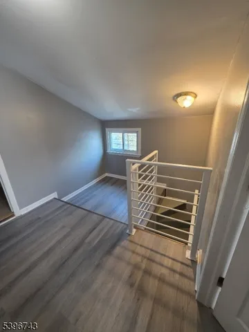 a view of an empty room with wooden floor and windows