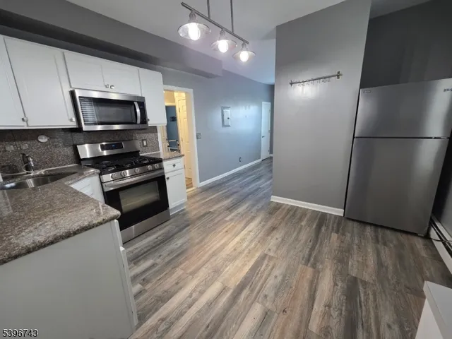 a kitchen with a refrigerator stove and wooden floor