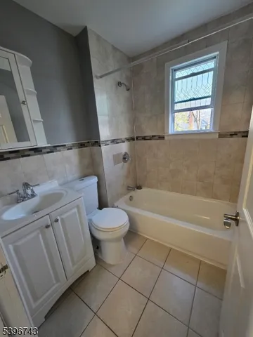 a bathroom with a granite countertop bathtub shower sink vanity and toilet