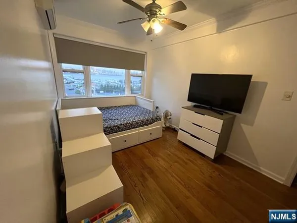 a bedroom with a bed and a flat tv screen on the dresser