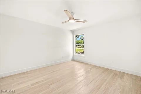 an empty room with a window and ceiling fan