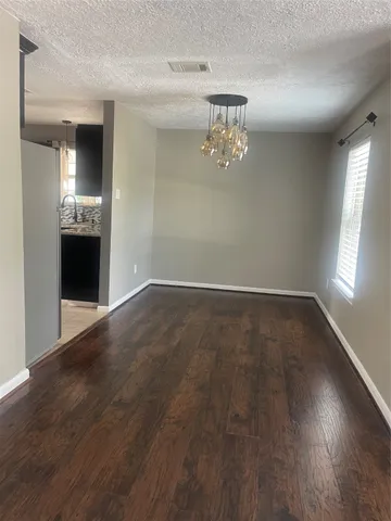an empty room with wooden floor and chandelier