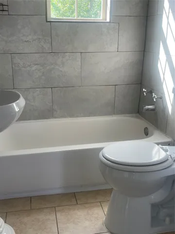 a bathroom with a white toilet and bathtub