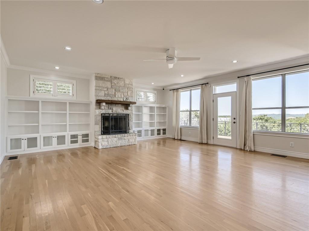267 North Commons Ford Road Austin, TX 78733 - Photo 12 of 34 Unfurnished living room featuring ceiling fan, a stone fireplace, light wood-style flooring, and recessed lighting