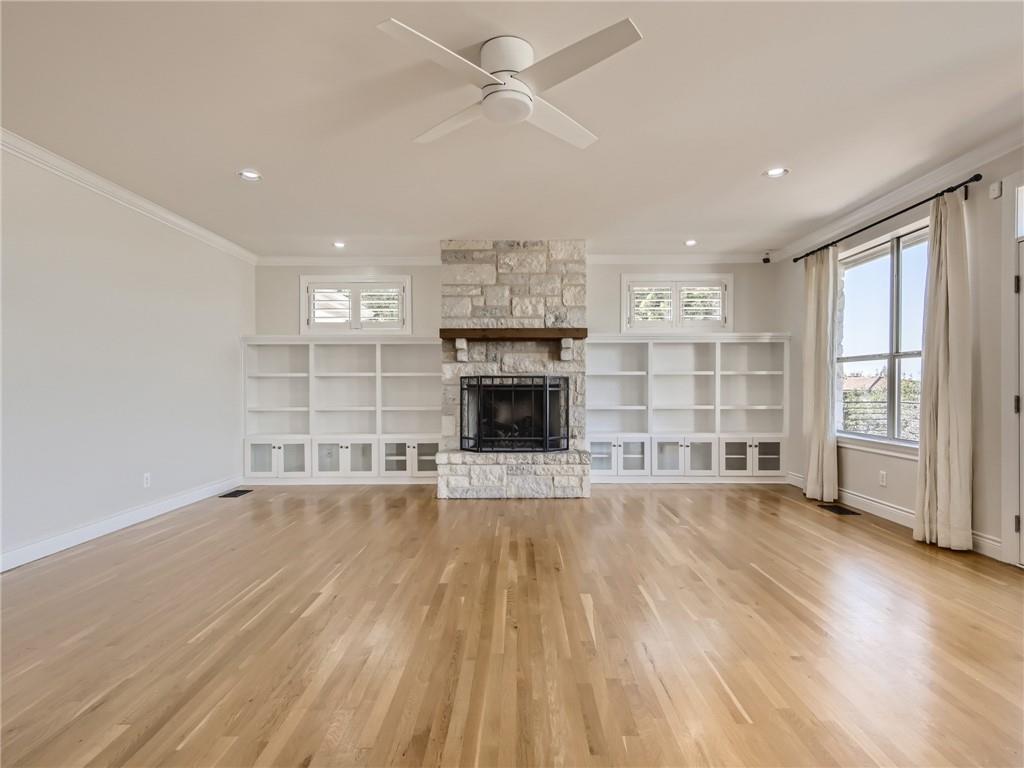 267 North Commons Ford Road Austin, TX 78733 - Photo 13 of 34 Unfurnished living room featuring light wood finished floors, ornamental molding, ceiling fan, and a fireplace
