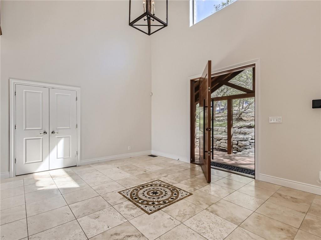 267 North Commons Ford Road Austin, TX 78733 - Photo 4 of 34 Foyer entrance with a high ceiling, light tile patterned floors, and suspended lighting