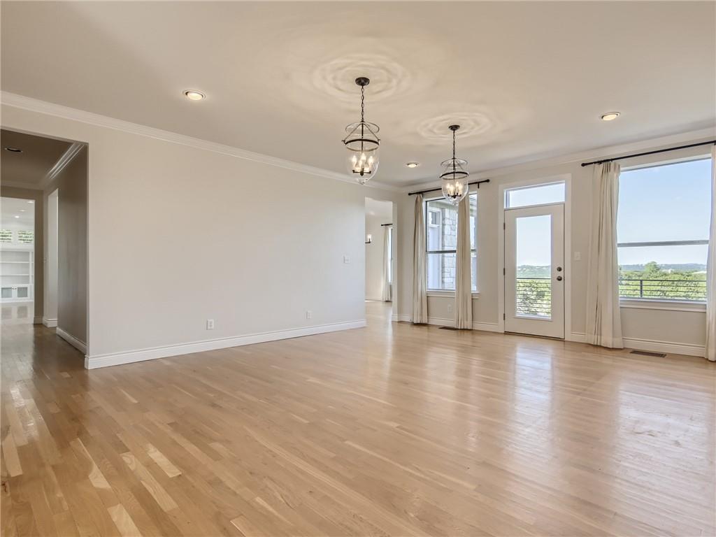 267 North Commons Ford Road Austin, TX 78733 - Photo 7 of 34 Empty room with suspended lighting, light wood-type flooring, and ornamental molding