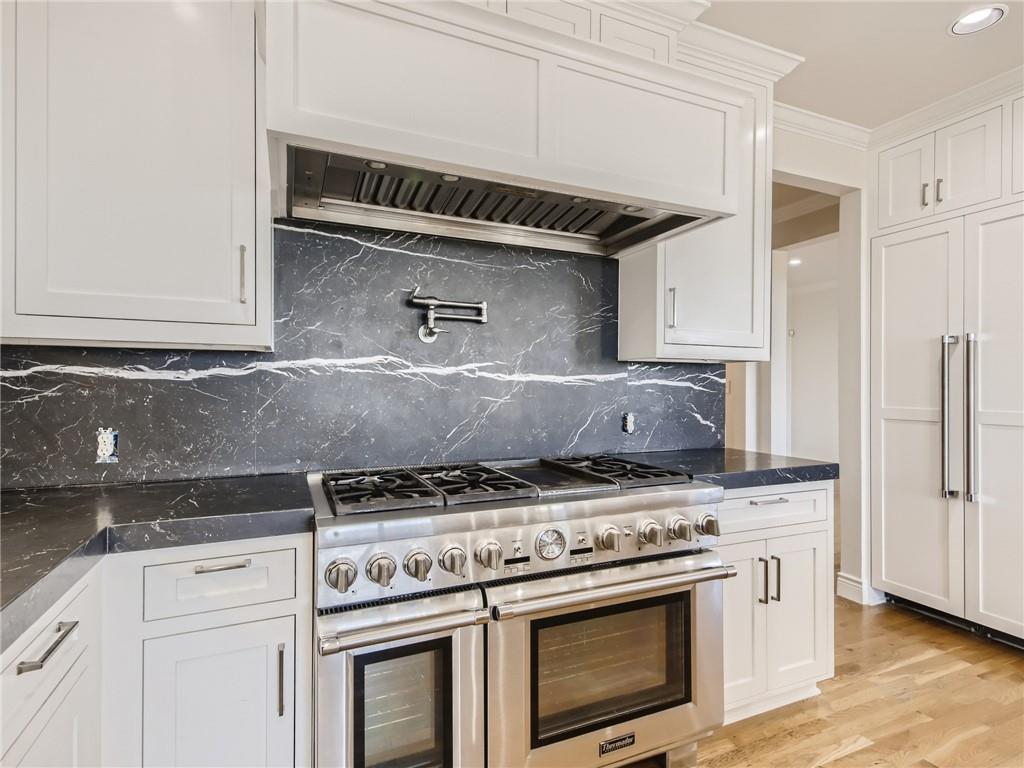 267 North Commons Ford Road Austin, TX 78733 - Photo 9 of 34 Kitchen with premium appliances, white cabinets, light wood-style flooring, dark stone counters, and recessed lighting