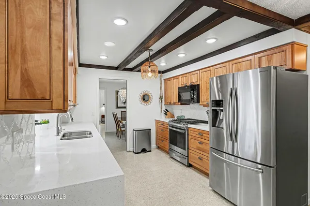 a kitchen with stainless steel appliances kitchen island granite countertop a refrigerator and a sink