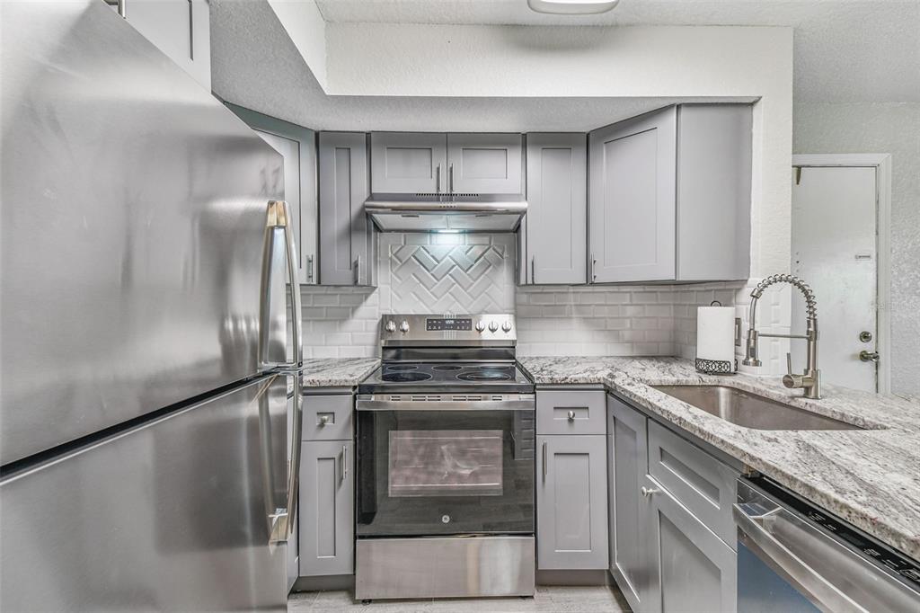 5111 Amulet Drive, Unit 104 New Port Richey, FL 34652 - Photo 21 of 74 a kitchen with granite countertop a stove and a refrigerator