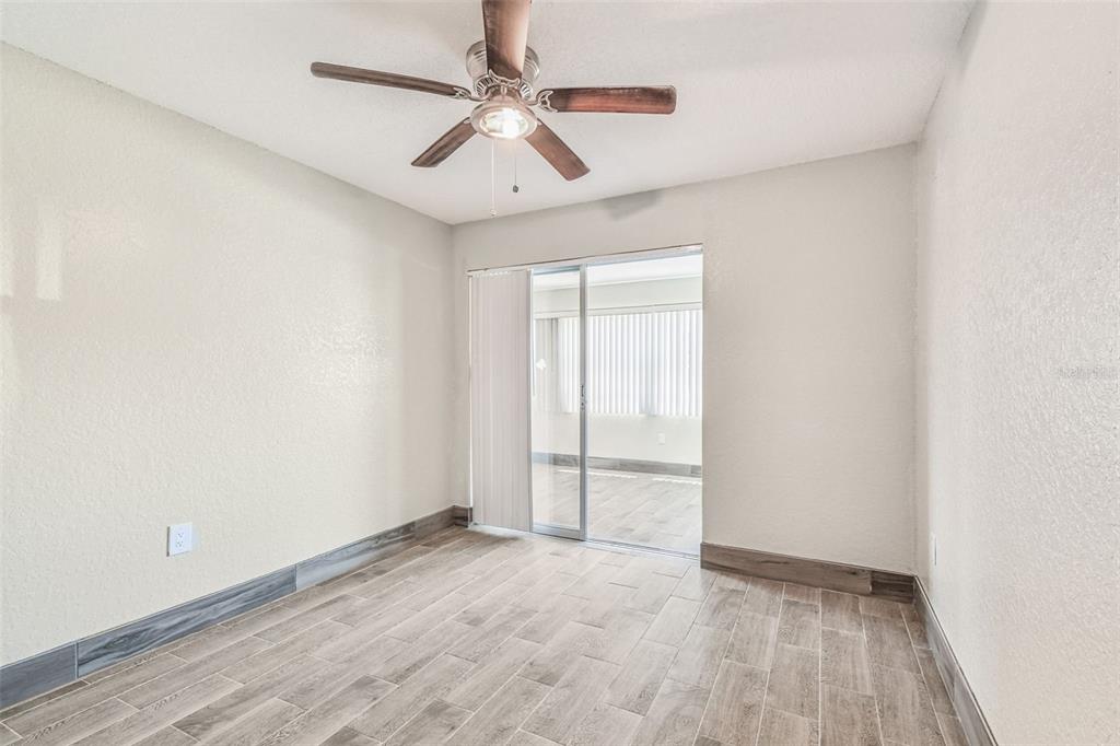 5111 Amulet Drive, Unit 104 New Port Richey, FL 34652 - Photo 27 of 74 an empty room with wooden floor and ceiling fan