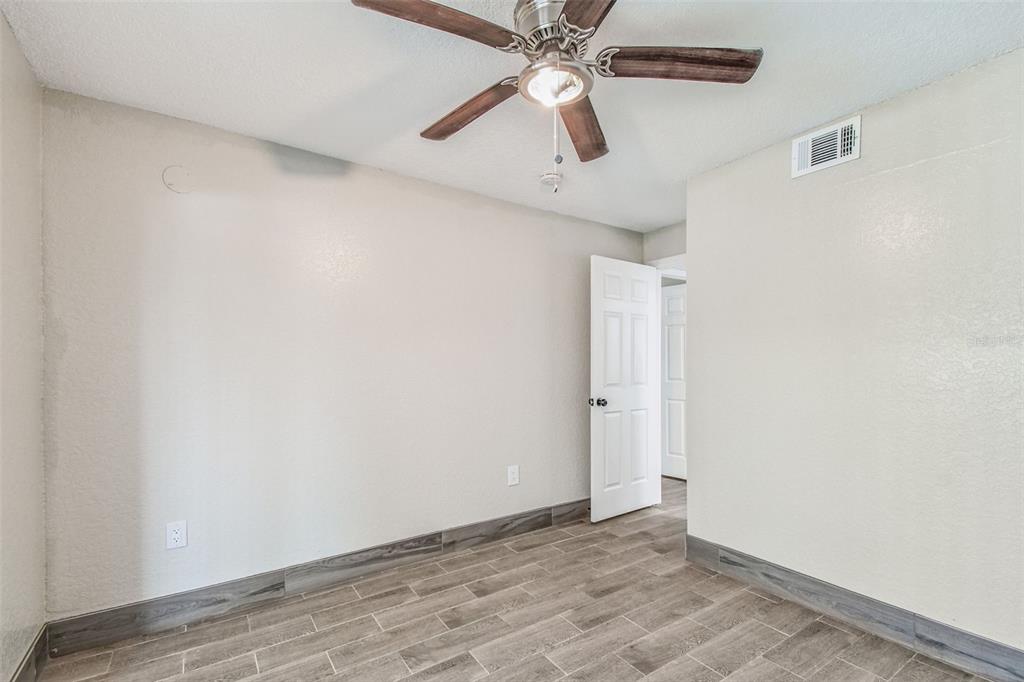 5111 Amulet Drive, Unit 104 New Port Richey, FL 34652 - Photo 29 of 74 an empty room with a ceiling fan and wooden floor