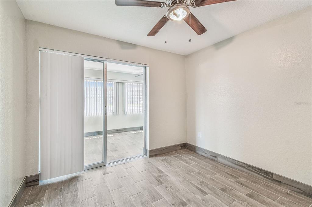 5111 Amulet Drive, Unit 104 New Port Richey, FL 34652 - Photo 30 of 74 an empty room with wooden floor fan and windows