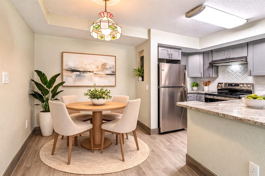 5111 Amulet Drive, Unit 104 New Port Richey, FL 34652 - Photo 3 of 74 a kitchen with stainless steel appliances granite countertop a dining table chairs and a refrigerator
