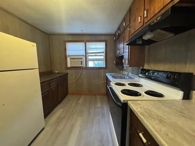 a kitchen that has a sink a stove top oven a refrigerator and a window