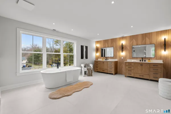 a bathroom with a tub a double vanity sink a mirror and a bathtub