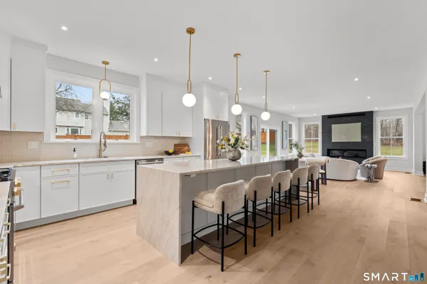 a large white kitchen with lots of counter space dining table and stainless steel appliances