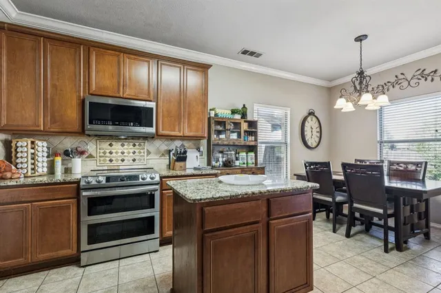 a open kitchen with stainless steel appliances granite countertop a stove top oven a sink dishwasher a dining table and chairs with wooden floor