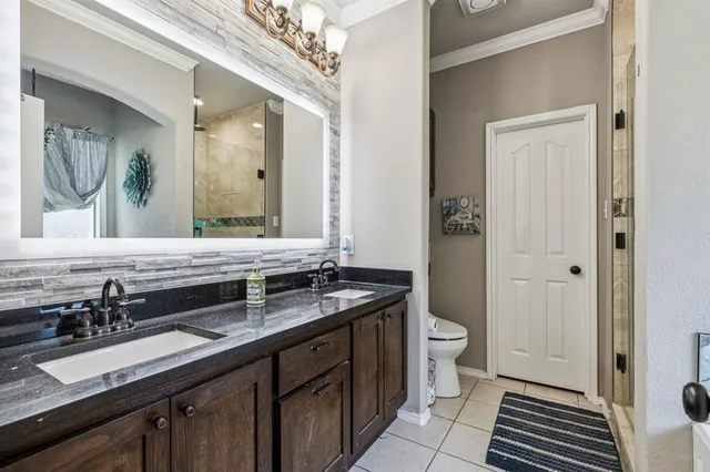 a bathroom with a granite countertop sink a large mirror a toilet and a shower