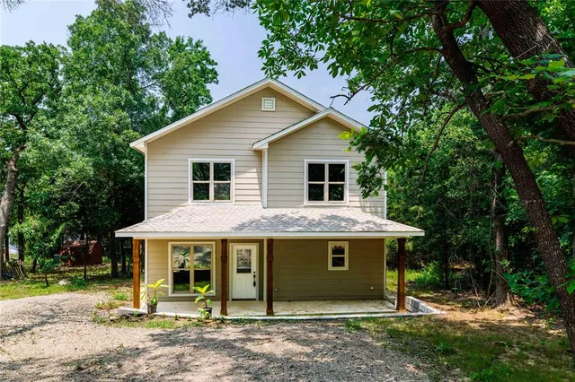a view of a house with a yard and large tree