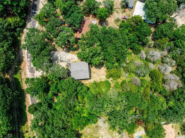 an aerial view of a house with a yard and trees all around