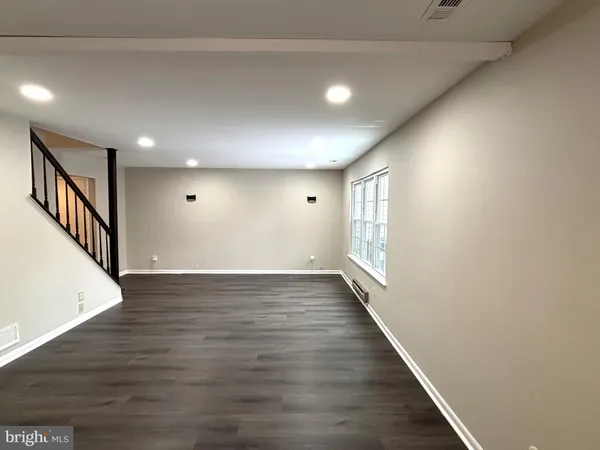 a view of an empty room with wooden floor and stairs