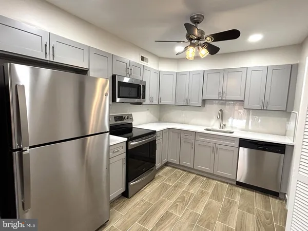 a kitchen with granite countertop a refrigerator a sink a stove a microwave and cabinets
