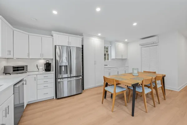 a kitchen with stainless steel appliances kitchen island granite countertop a dining table chairs and refrigerator