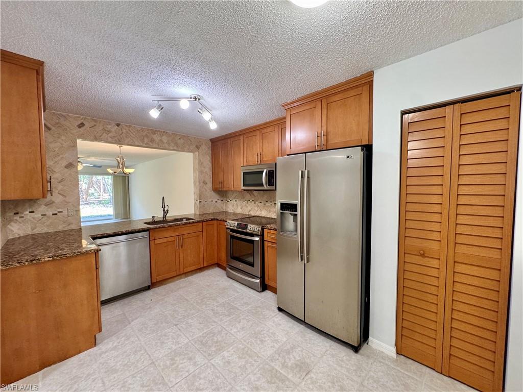 661 Squire Circle, Unit 101 Naples, FL 34104 - Photo 17 of 25 a kitchen with stainless steel appliances granite countertop a refrigerator a sink and a stove
