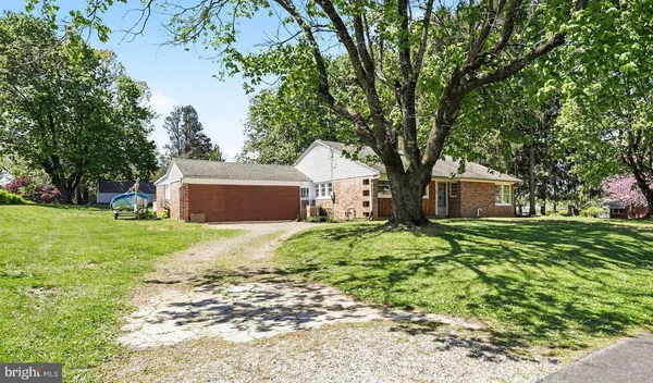 a front view of a house with a garden and trees