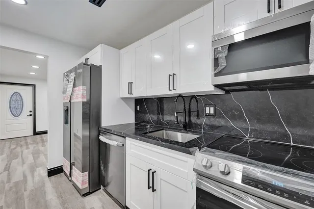 a kitchen with stainless steel appliances granite countertop a sink and a refrigerator
