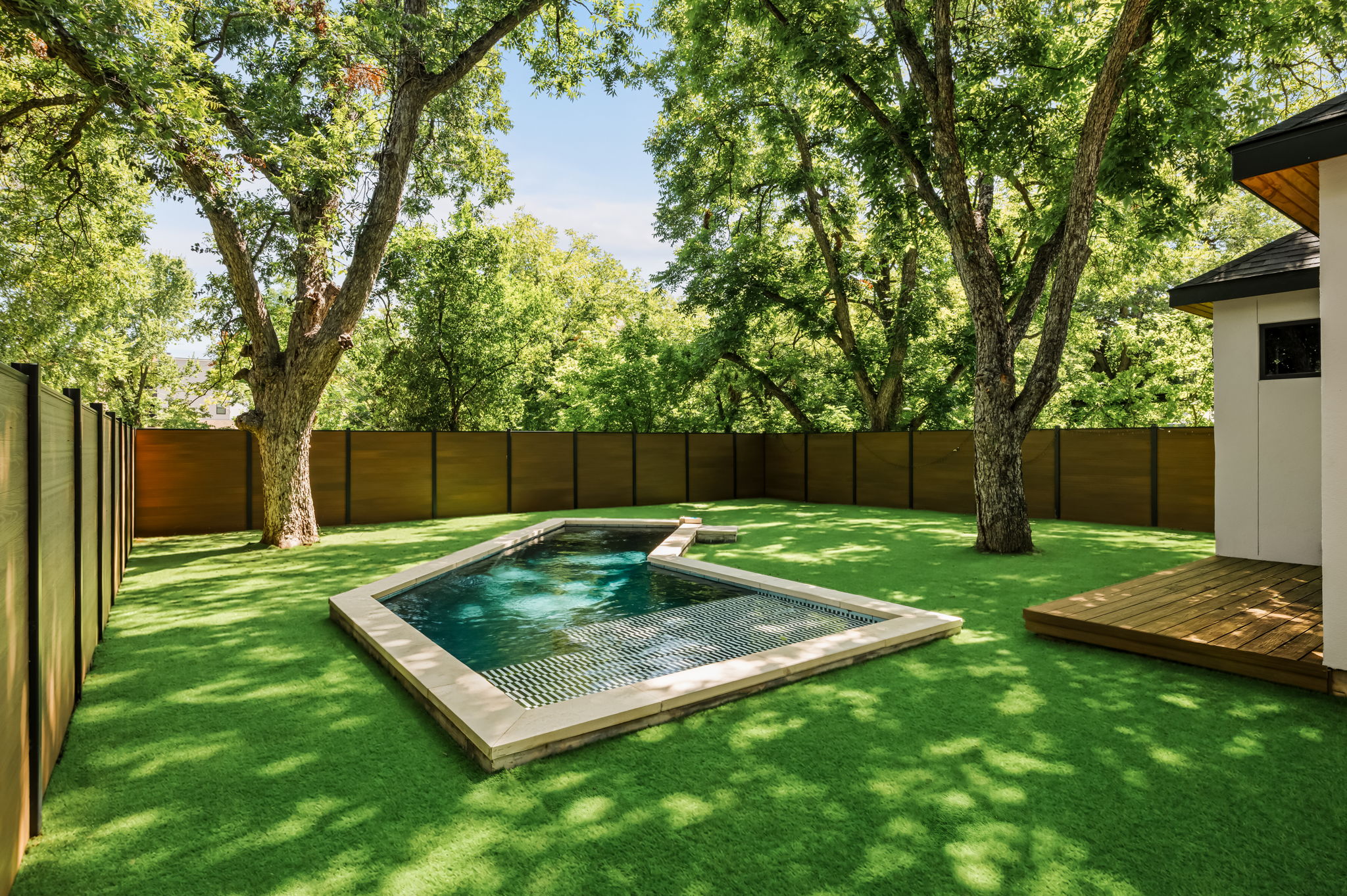 3210 Thompson Street Austin, TX 78702 - Photo 2 of 39 A private yard with lush green turf surrounds a sleek in-ground pool, complemented by mature trees.