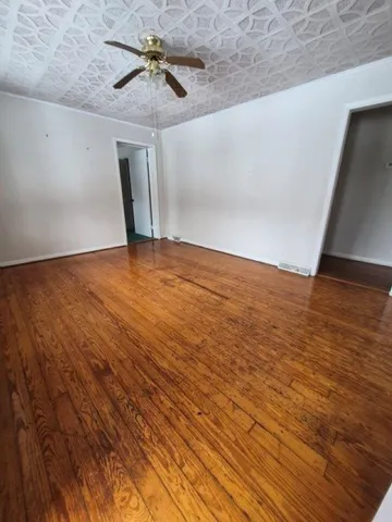 a view of a room with wooden floor a ceiling fan and a window