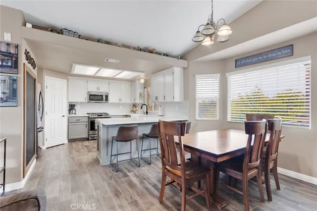 a kitchen with kitchen island a counter top space wooden floor stainless steel appliances and cabinets
