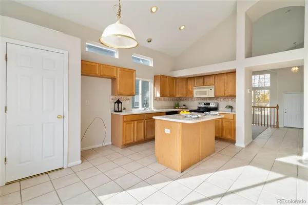 a large kitchen with stainless steel appliances kitchen island granite countertop a refrigerator and a sink