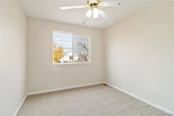 an empty room with a ceiling fan and a window